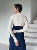 caraucci-woman-wearing-cream-sleeve-shrug-layered-over-navy-dress-with-thumbhole-detail #color_cream
