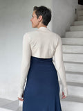 caraucci-woman-wearing-cream-sleeve-shrug-layered-over-navy-dress-with-thumbhole-detail #color_cream